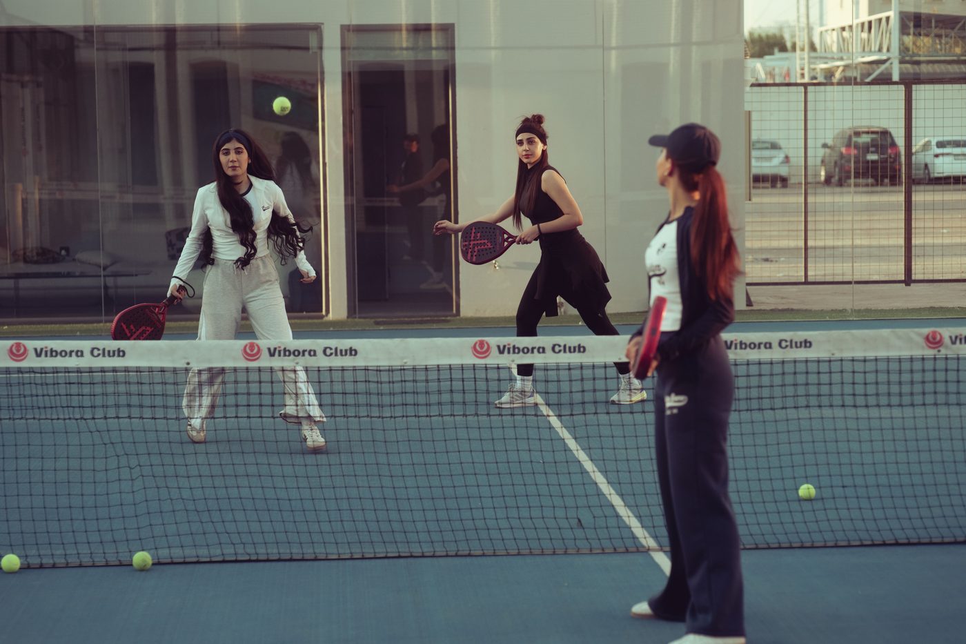 A doubles match in progress on a blue padel court